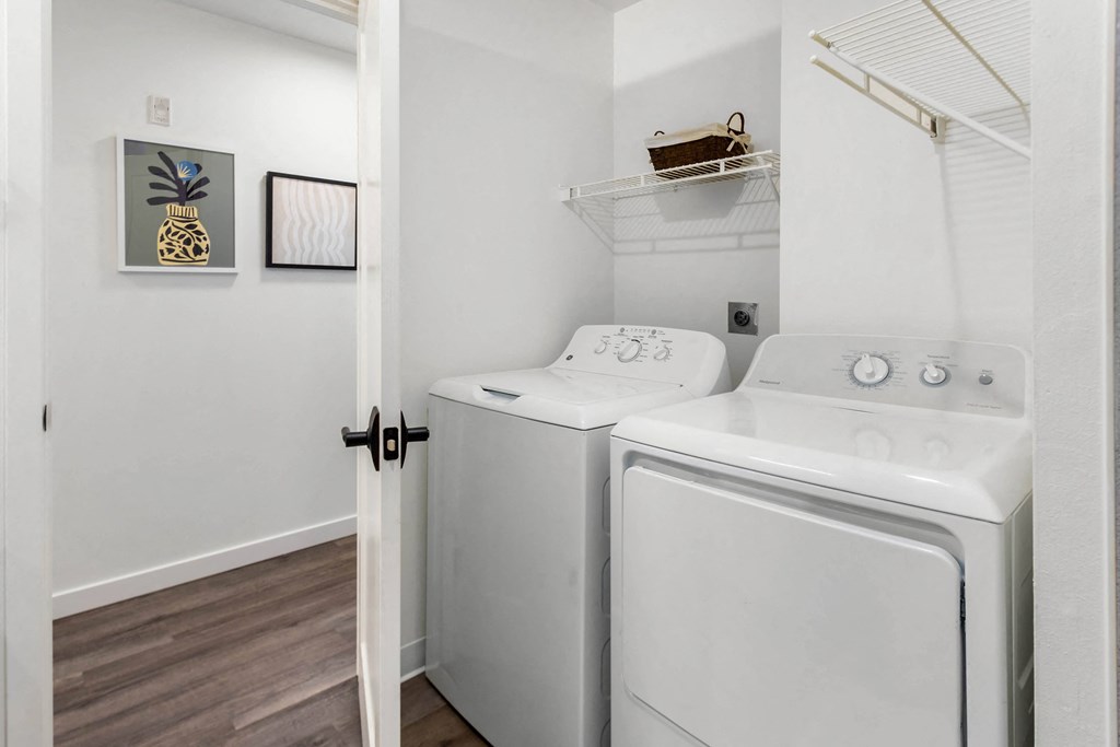 a white washer and dryer in a white laundry room with a door open