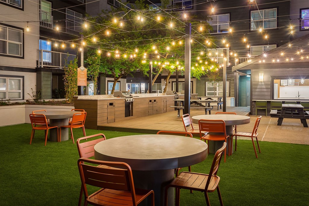 a patio with tables and chairs and string lights