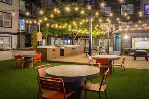 a patio with tables and chairs and string lights