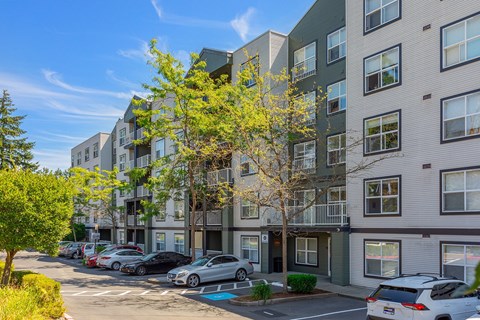 an apartment building with cars parked in a parking lot