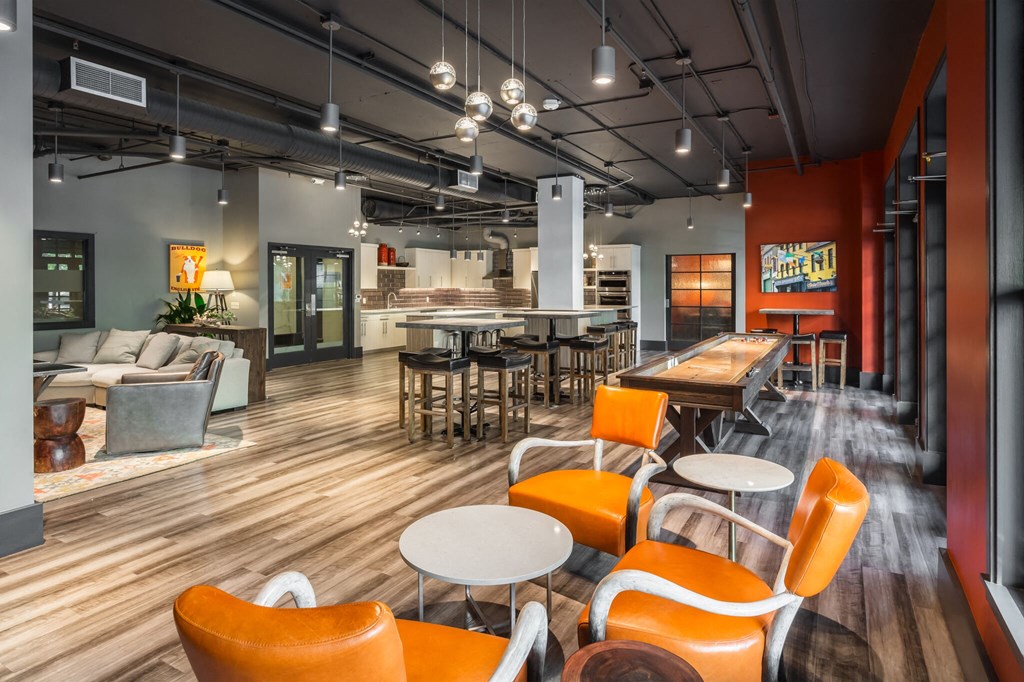 a lounge area with chairs and tables and a kitchen