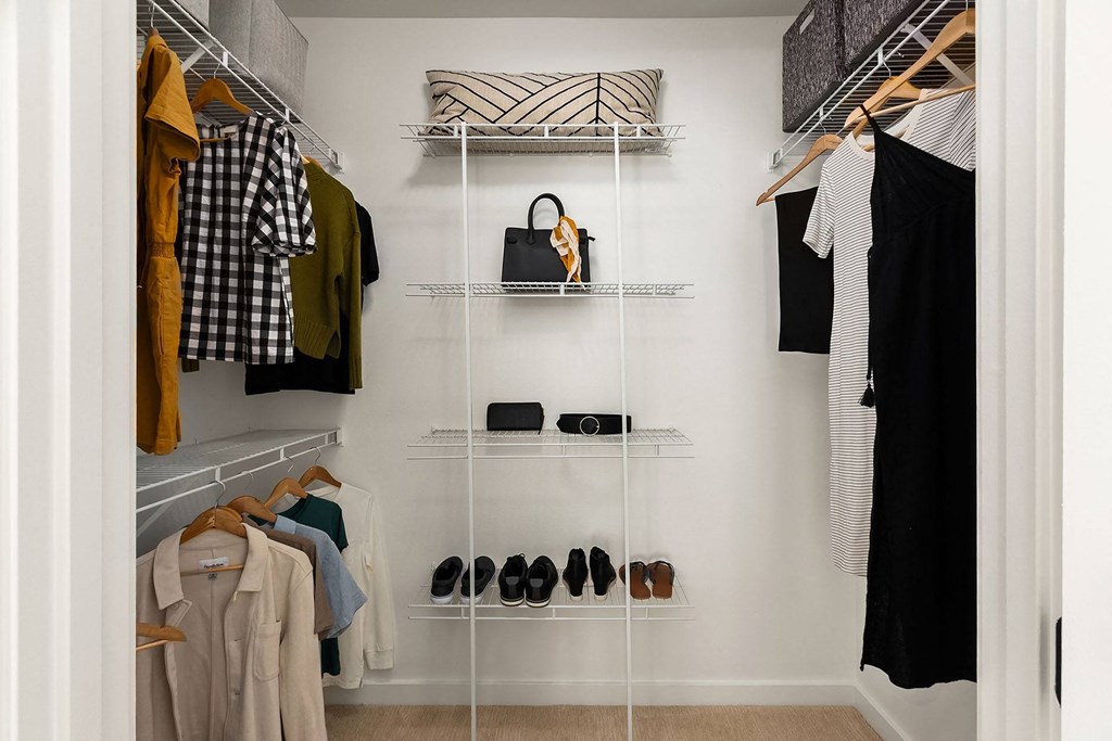 a walk in closet with a rack of clothes and shoes
