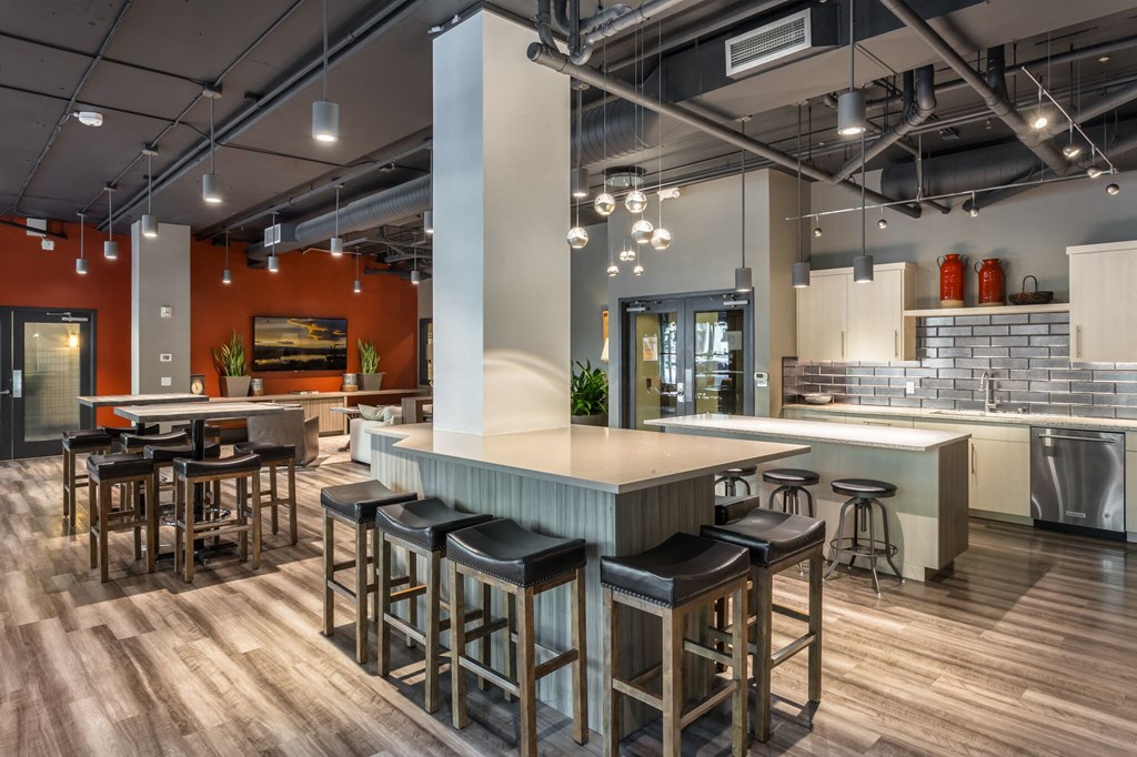 a communal kitchen and dining area with bar stools and tables
