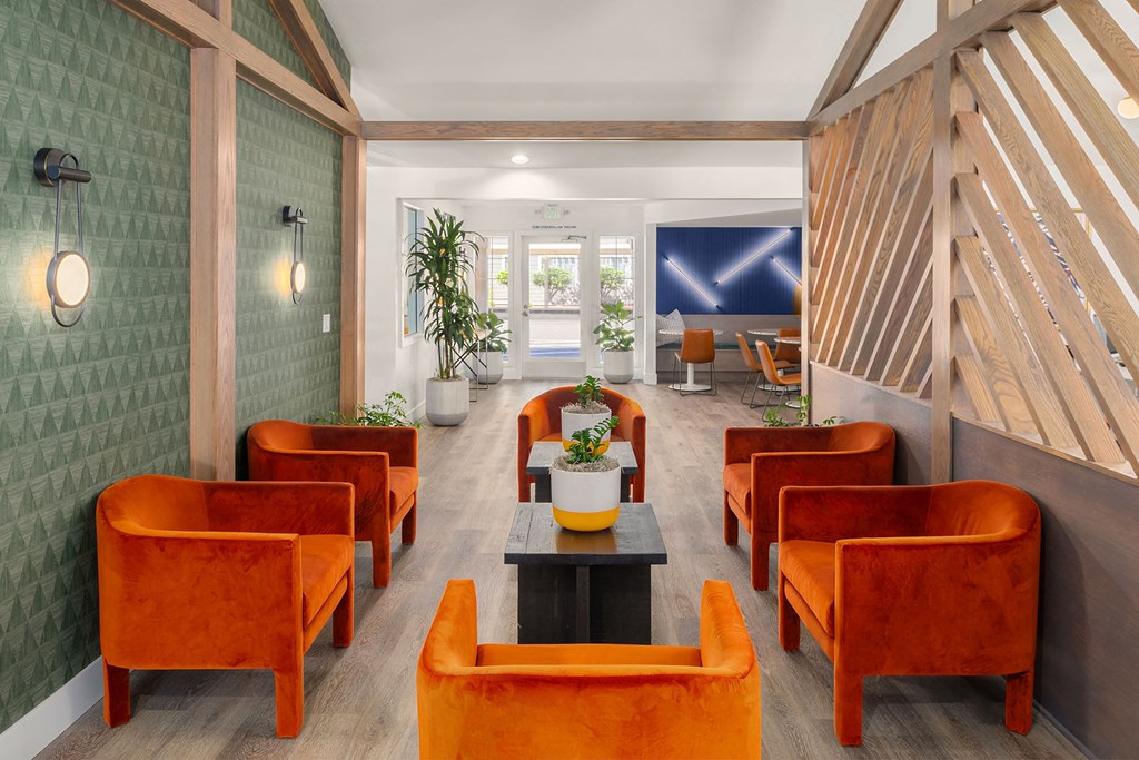 a lobby with orange chairs and a table