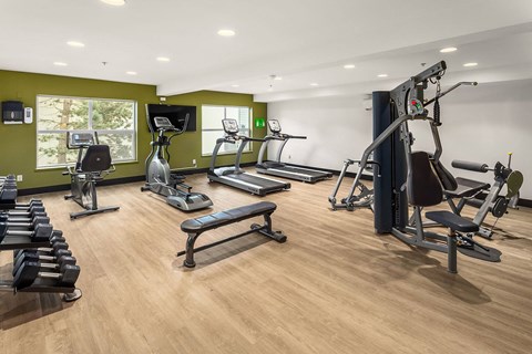 a gym with cardio equipment and weights on a wood floor