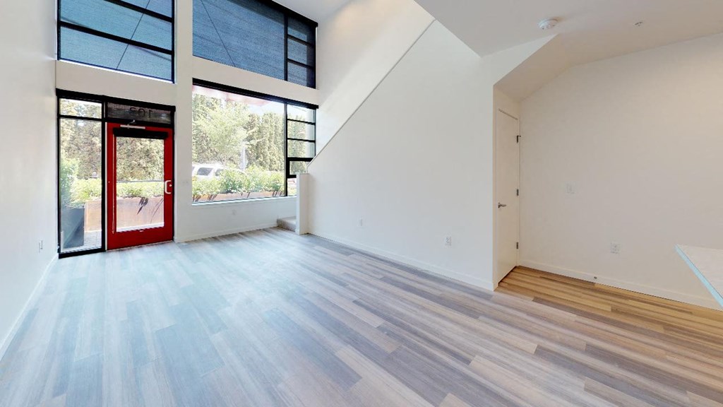 a large room with a red door and hardwood floors