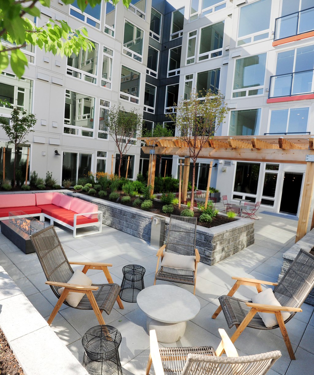 an outdoor patio with chairs and tables and a red couch