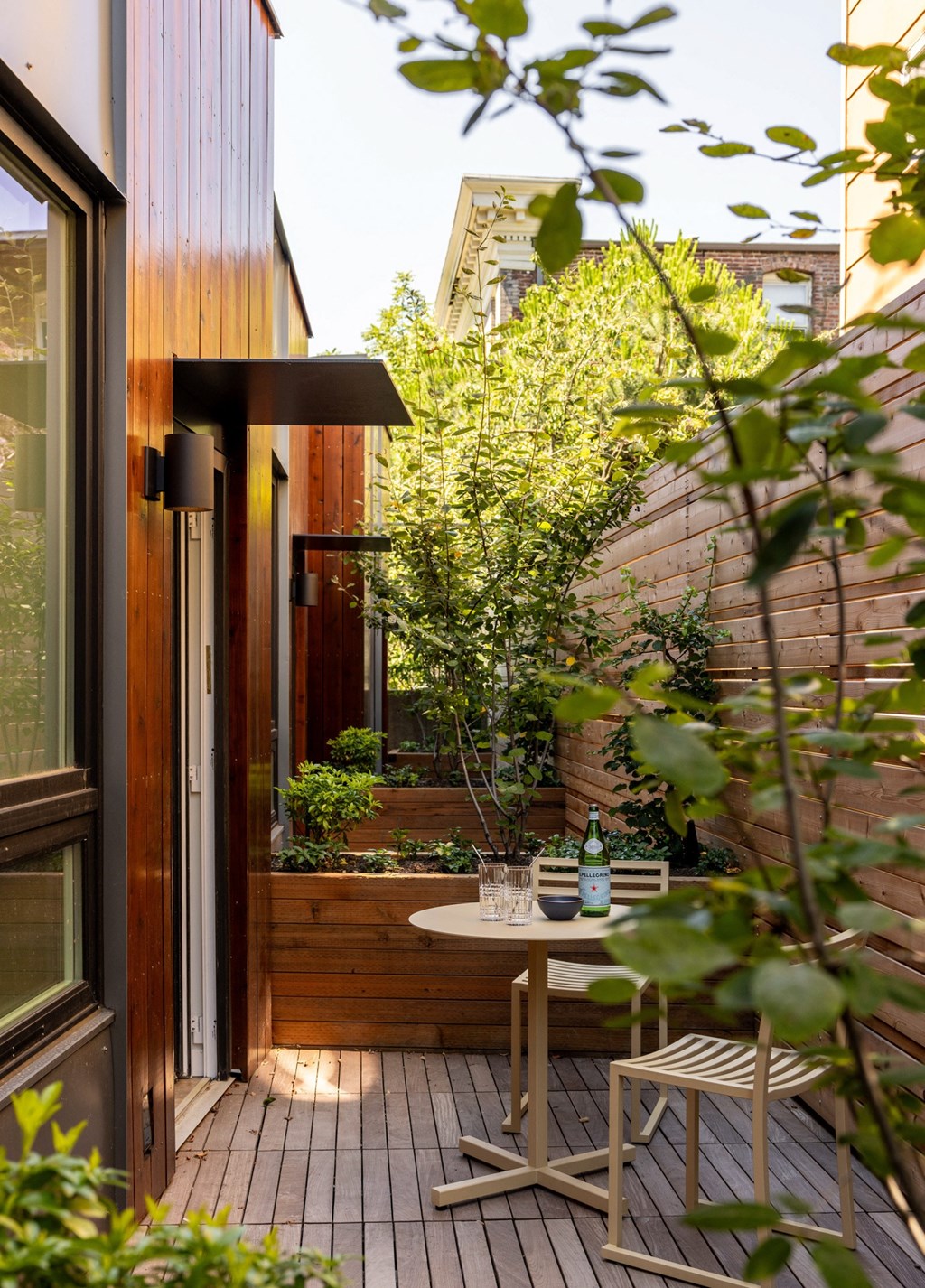 a small patio with a table and chairs and a tree