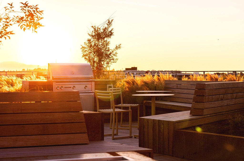 the sun sets on the roof of a restaurant with wooden benches and tables