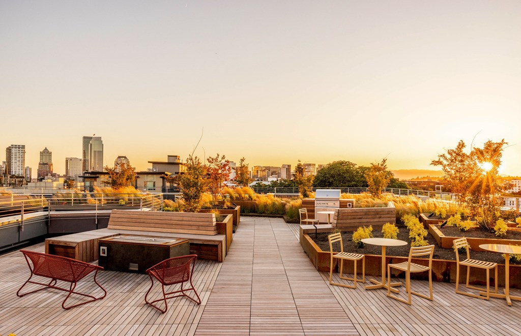 a roof terrace with tables and chairs and a city in the background