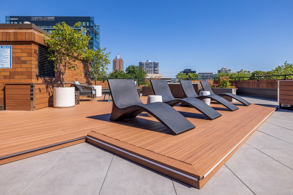 a row of black lounge chairs on a wooden deck on a roof