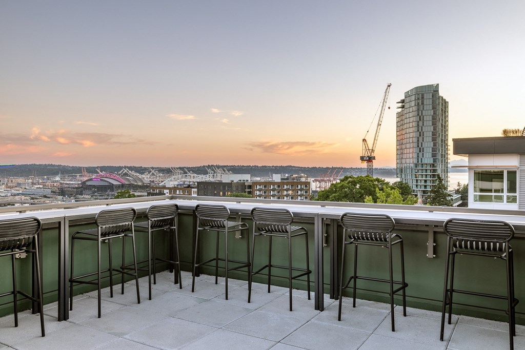 a view of the city from a balcony with bar stools