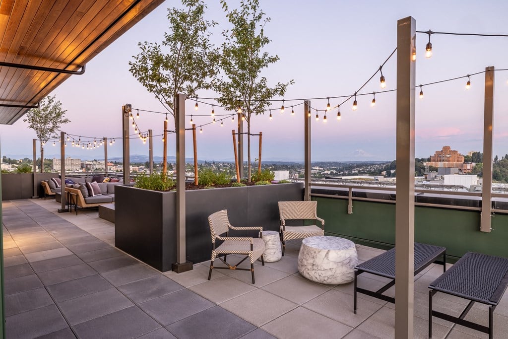 a rooftop terrace with tables and chairs and a view of the city
