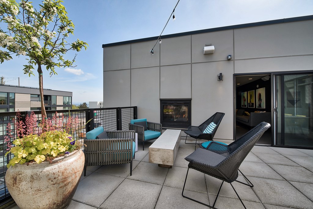 A patio with a table, chairs, and a fireplace.