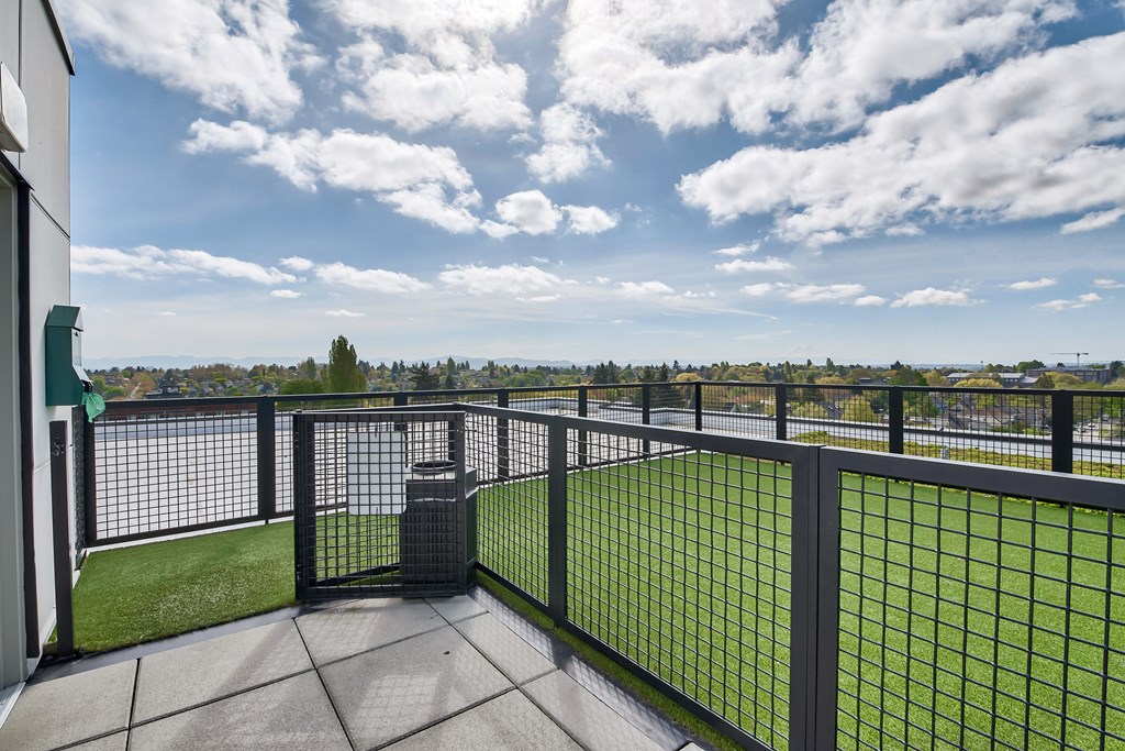 A balcony with a black railing and a green lawn.