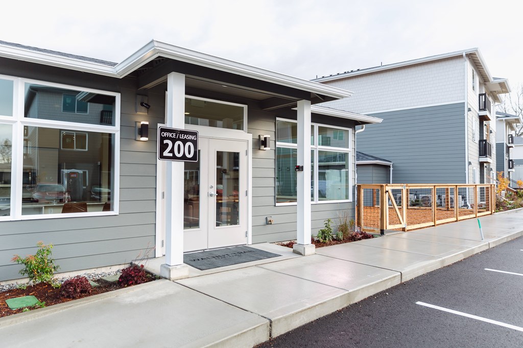 A modern building with a glass door and a sign that reads "Office Leasing 200".