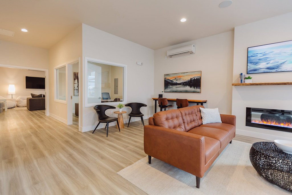 A living room with a brown leather couch and a fireplace.