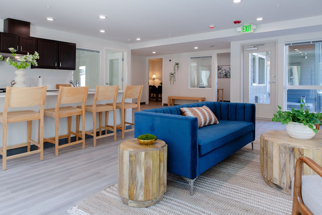 a living room with a blue couch and a dining room with wooden chairs