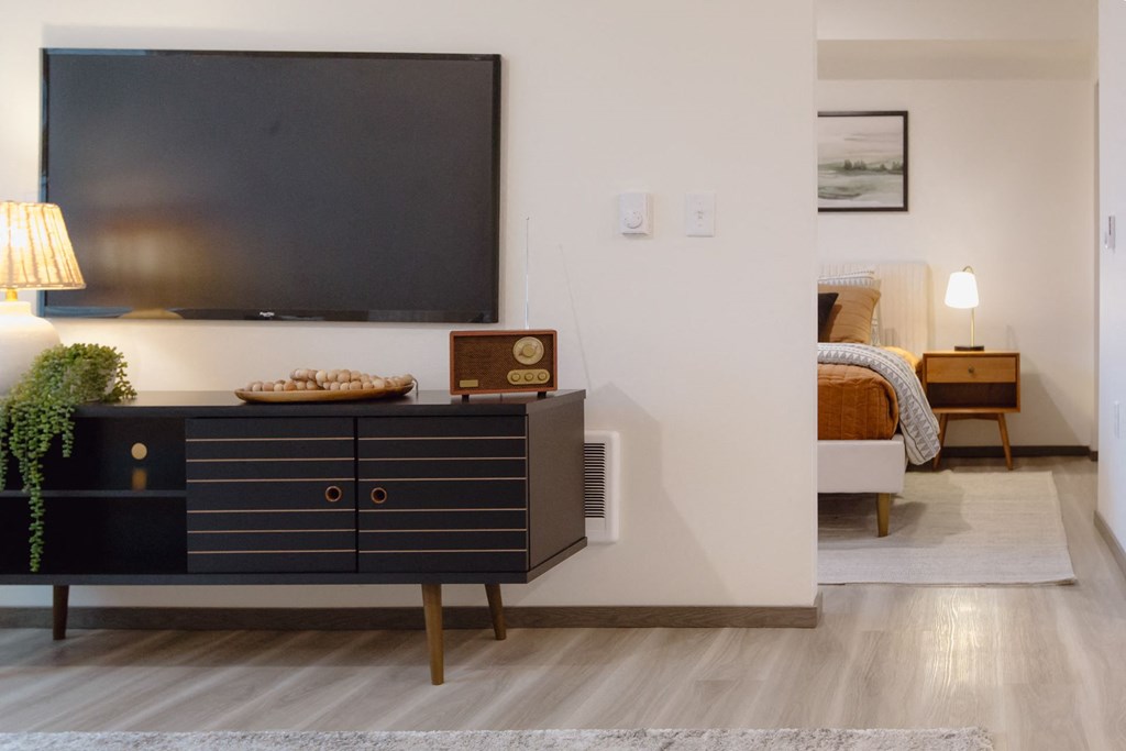 a living room with a tv and a bedroom in the background