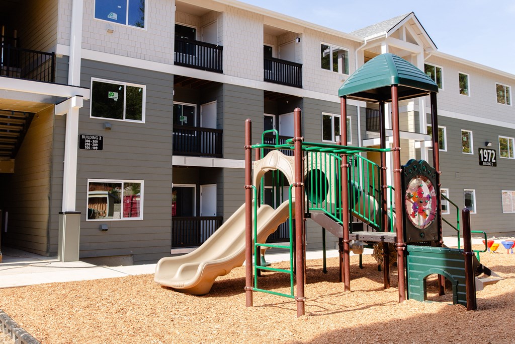 a playground with a slide in front of an apartment building