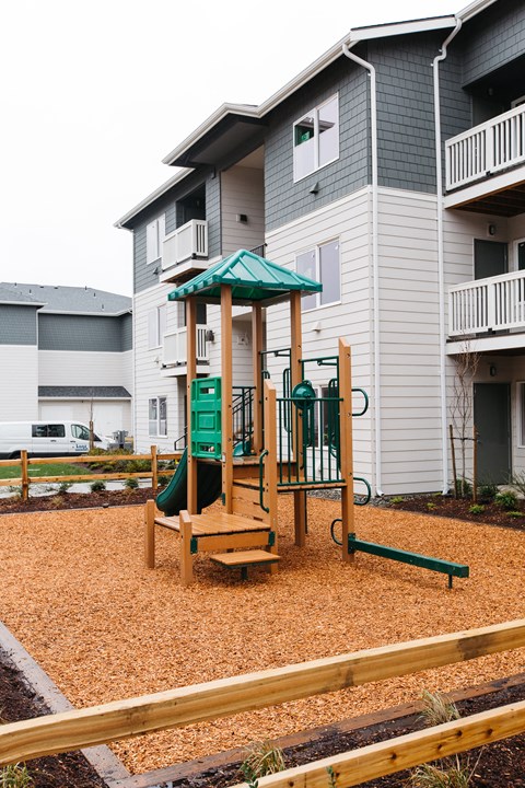 a playground with a swing set in front of an apartment building