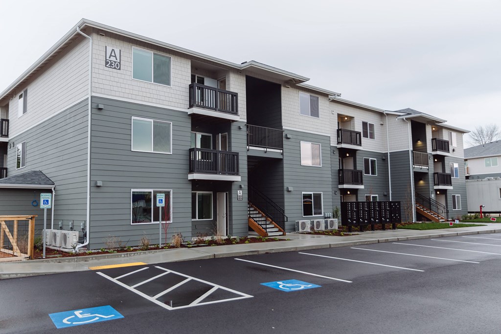 A parking lot in front of apartment building with a handicap parking space.
