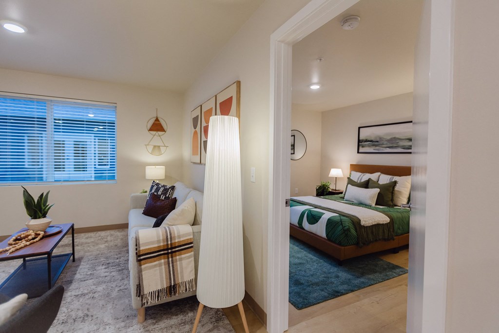 A well-lit bedroom with a bed, couch, and a table with a plant on it.