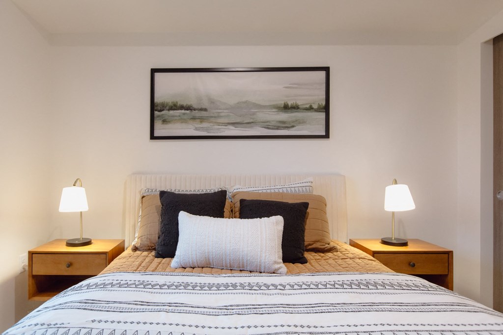 a bedroom with a bed with pillows and a picture on the wall