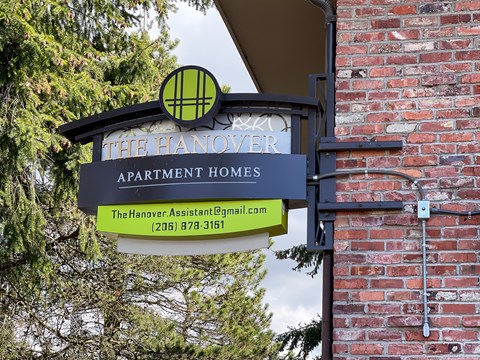 A sign for The Hanover Apartment Homes with a phone number and email address.