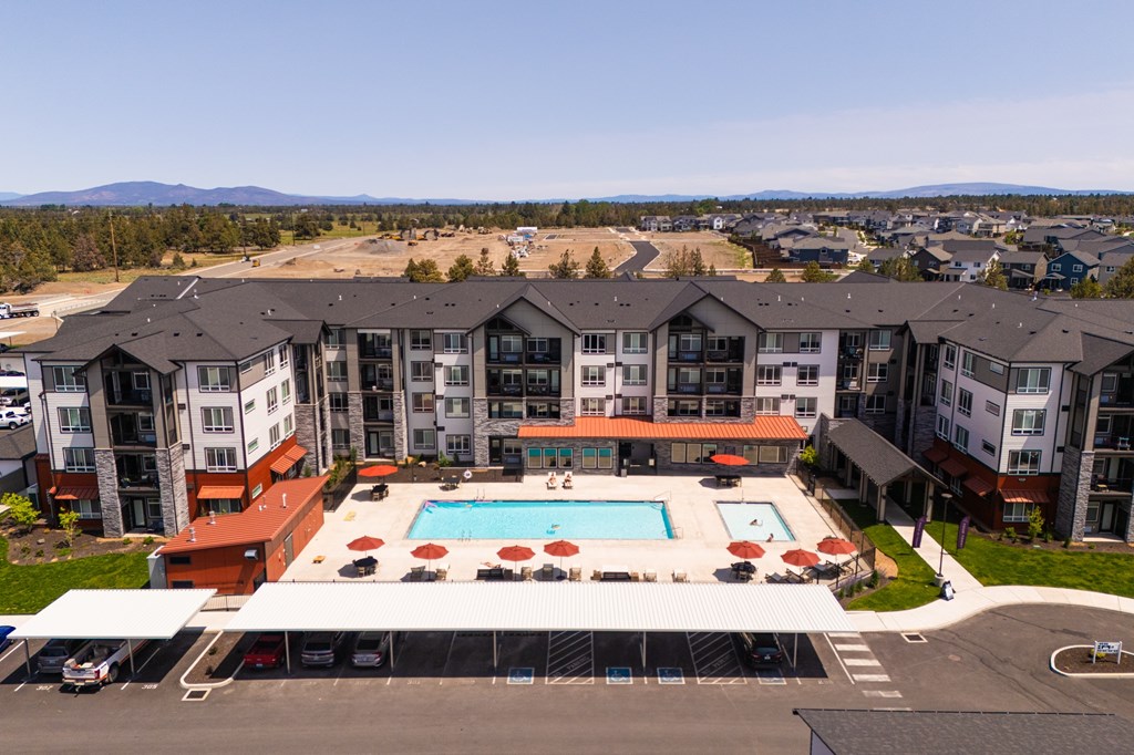 A large apartment complex with a swimming pool in the foreground.