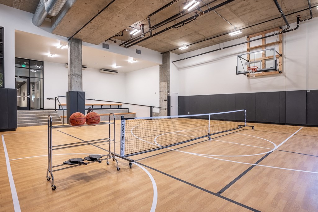 a basketball court in the center of a gym with two basketballs on the floor