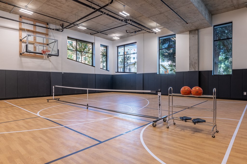 a basketball court in a gym with a basketball hoop and two balls on the floor