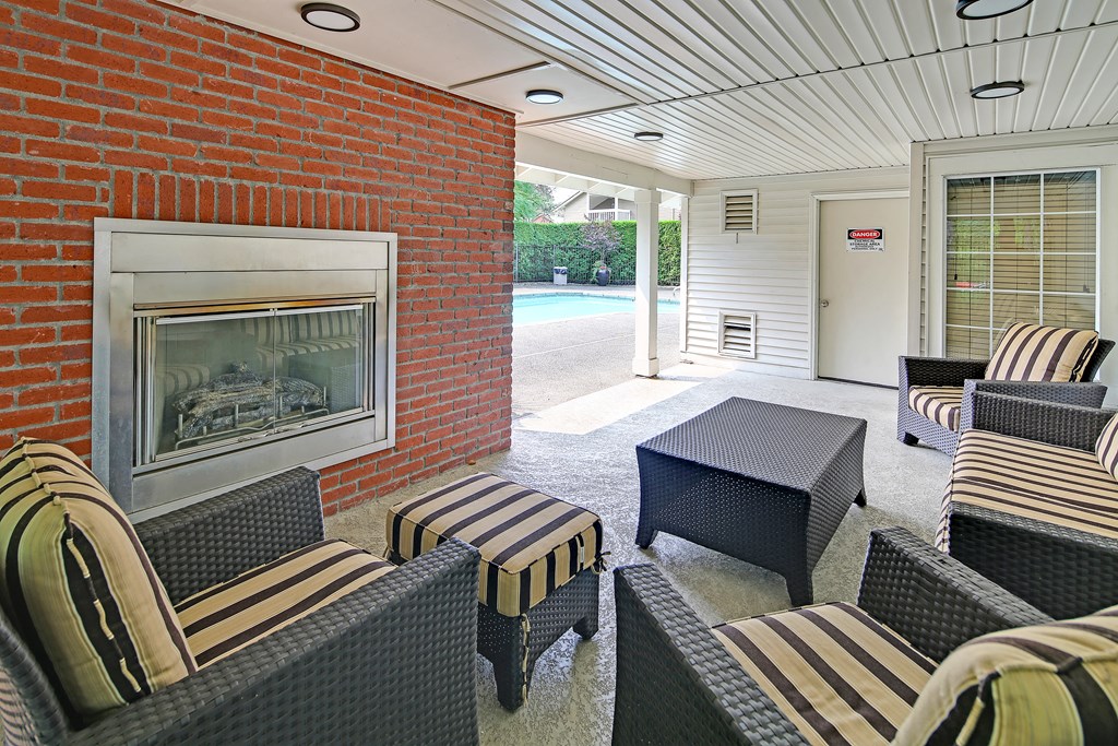 a porch with chairs and a fireplace and a pool