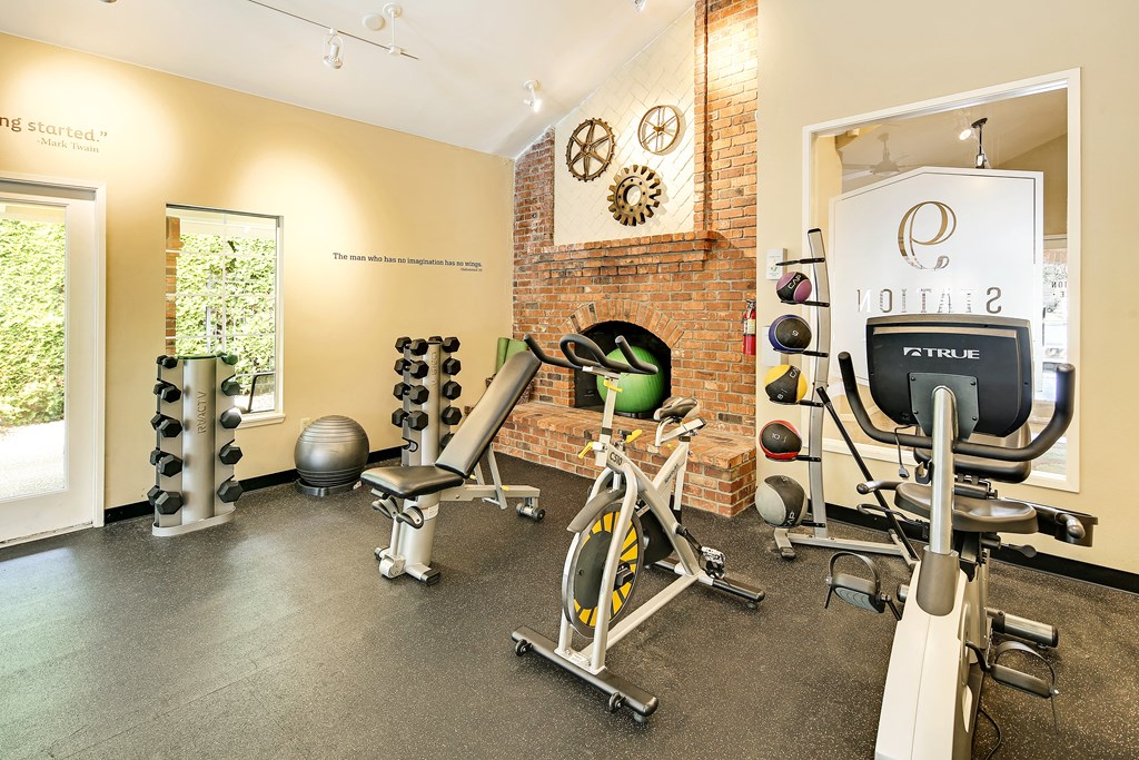 a gym with cardio equipment and weights on a brick wall