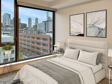 A bedroom with a large bed and a view of a city skyline.