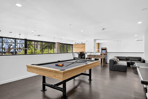 A pool table is in the middle of a room with a couch and a TV.