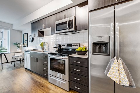 A modern kitchen with stainless steel appliances and wooden floors.