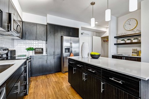 A modern kitchen with black cabinets and a white countertop.