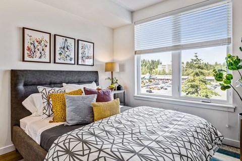 A bedroom with a large bed and a window overlooking a parking lot.