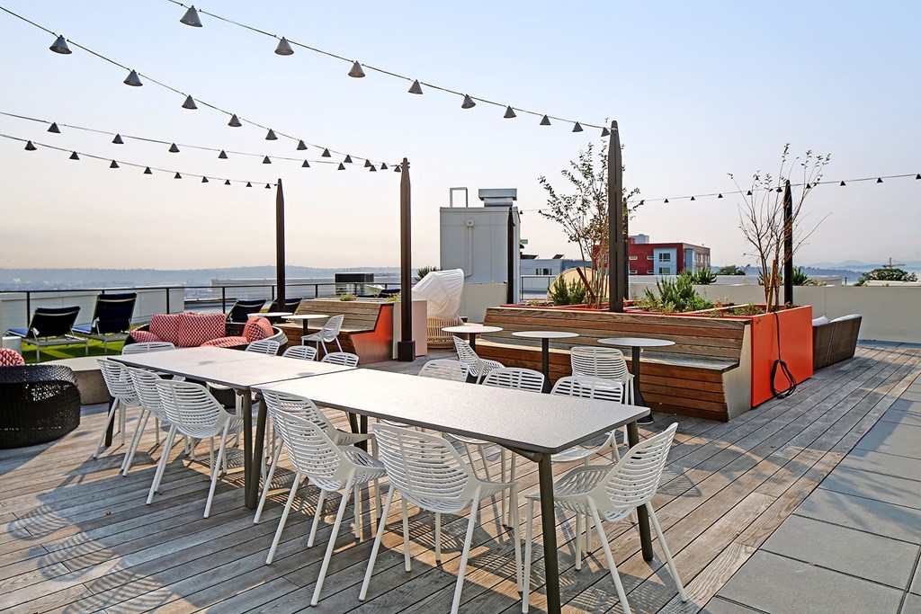 a rooftop patio with tables and chairs and a planter box