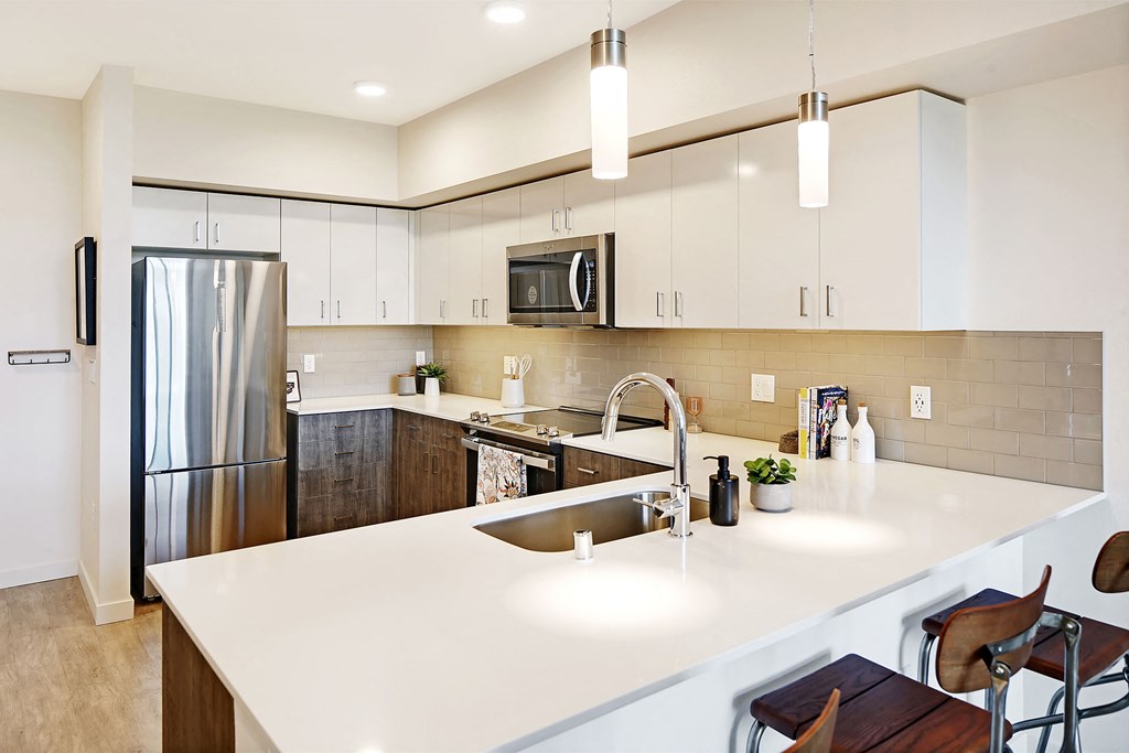 a large white kitchen with stainless steel appliances and white counter tops