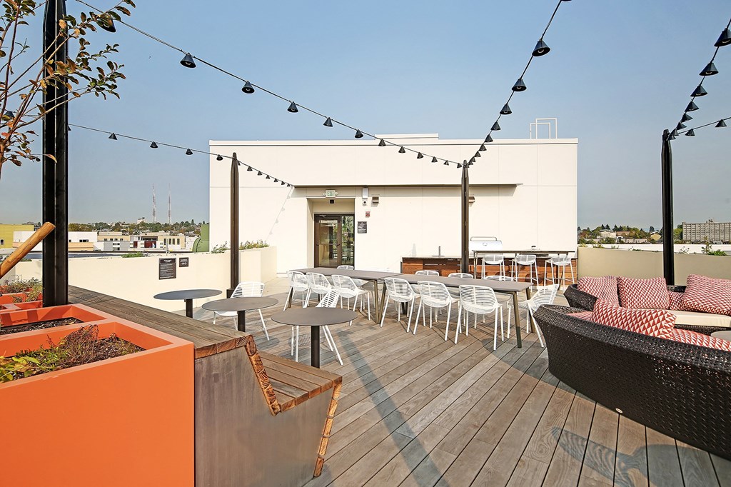 a rooftop patio with tables and chairs and a building in the background