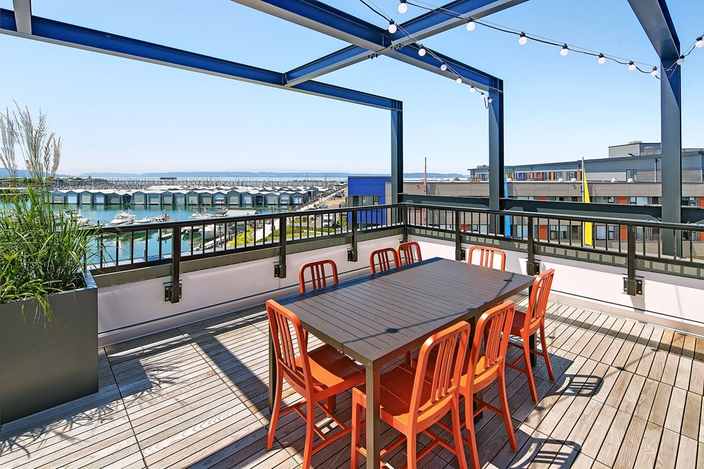 a dining area with a table and chairs on a balcony overlooking the water
