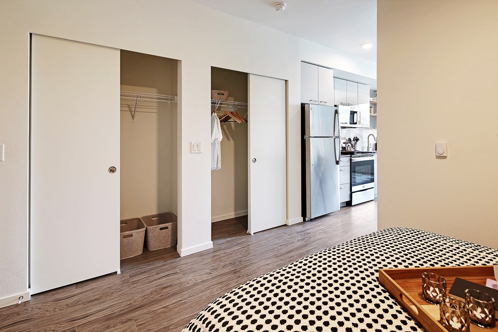a bedroom with a black and white checkered bed and a refrigerator and closet