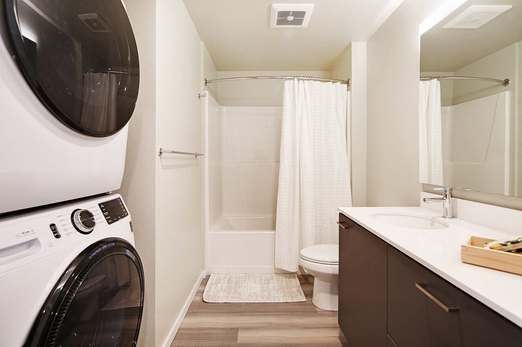 a washer and dryer in a bathroom with a toilet and a shower