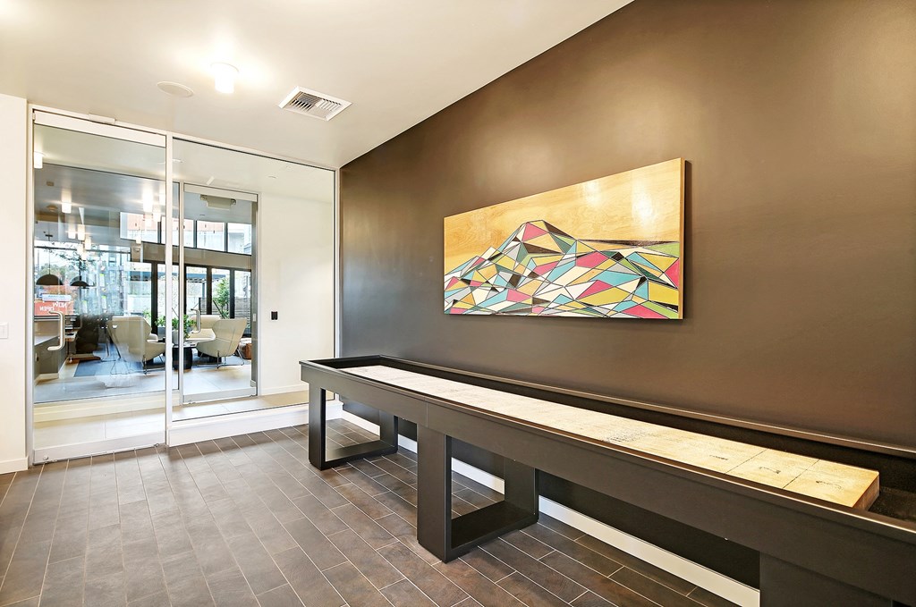 a hallway with a bench and a painting on a wall and a glass door