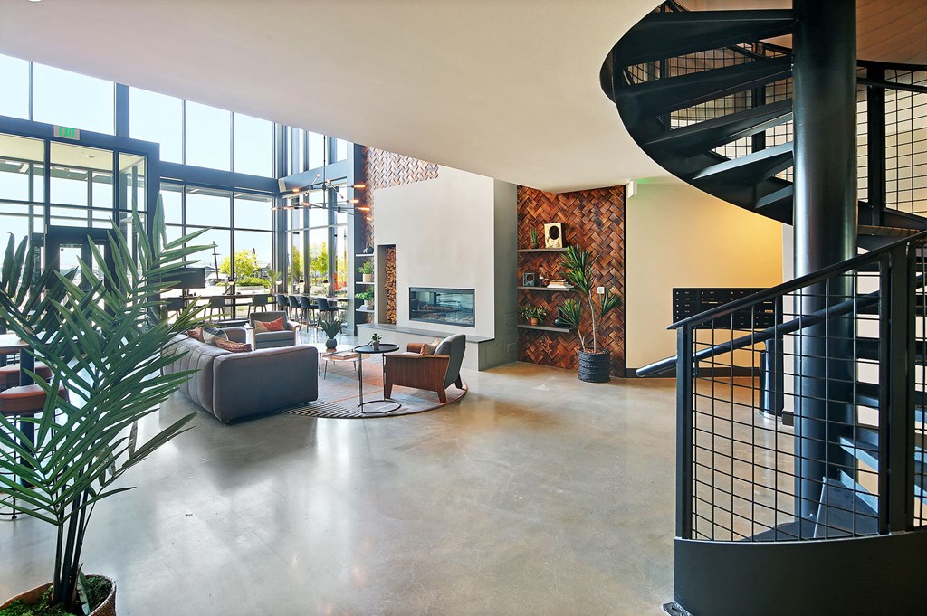 a large living room with a spiral staircase and a lobby with couches
