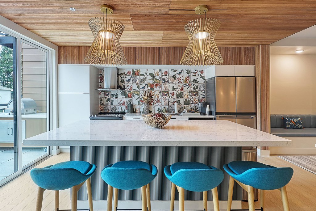 a kitchen with a large island with four blue chairs around it