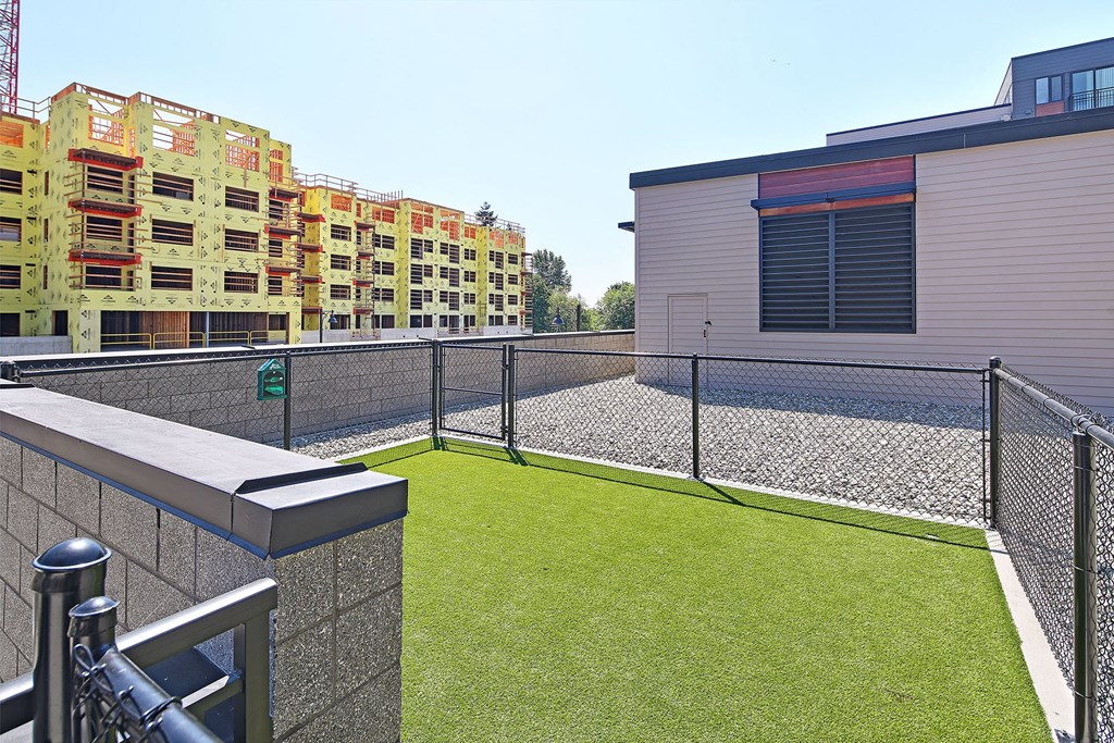 a fenced in area with a lawn in front of a building