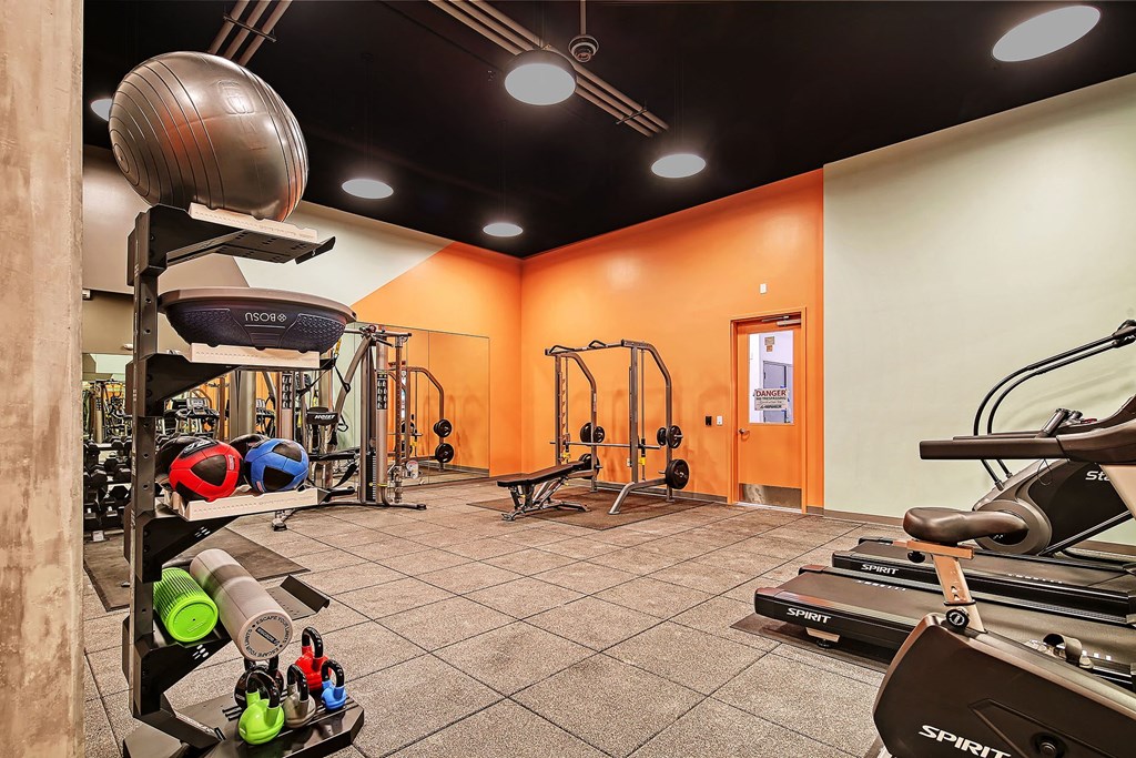 a gym with weights and other exercise equipment at the enclave at university crossings apartments